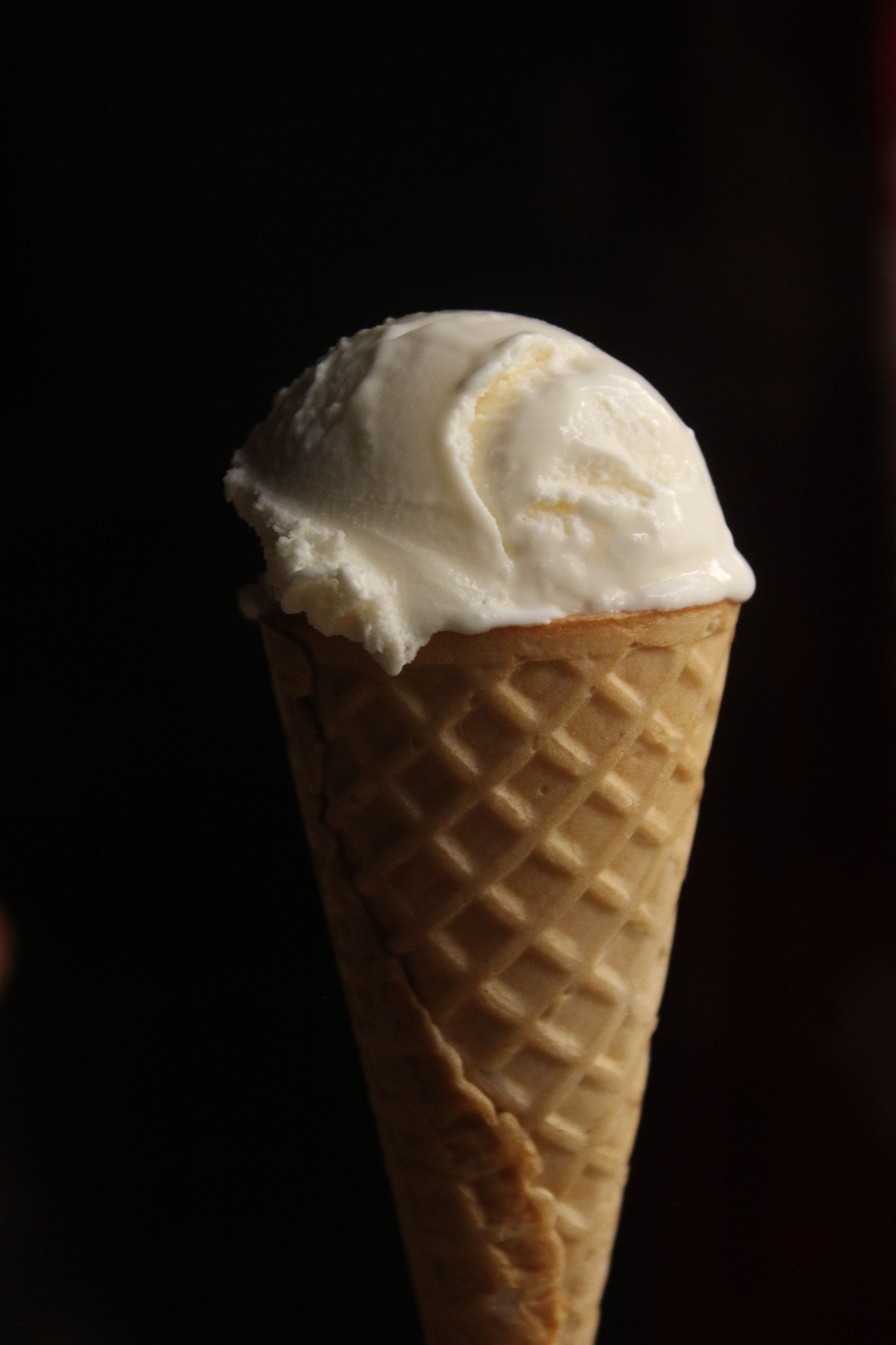 Vanilla ice cream in a cone against a dark background