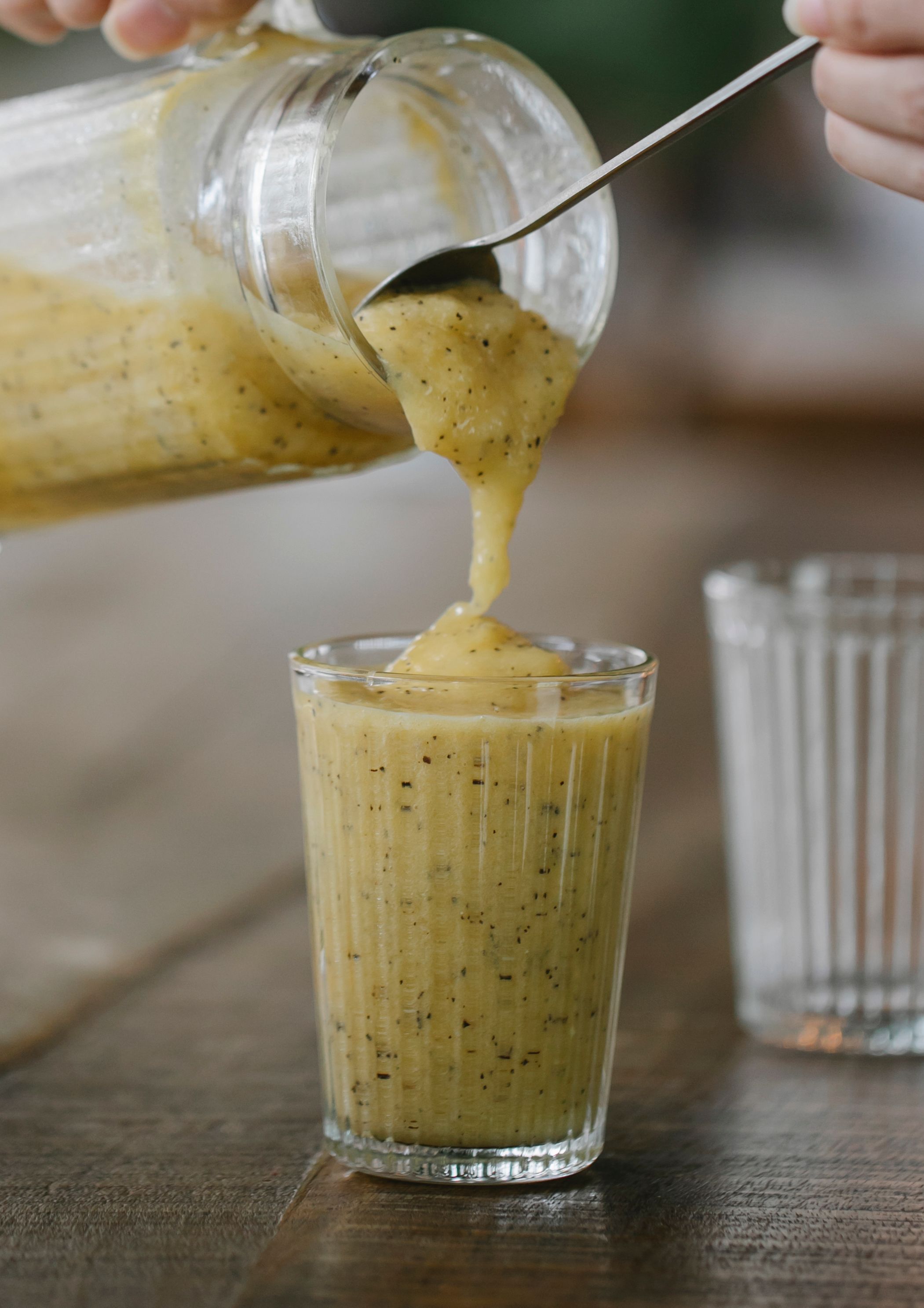Thick kiwi and banana smoothie being poured into a glass
